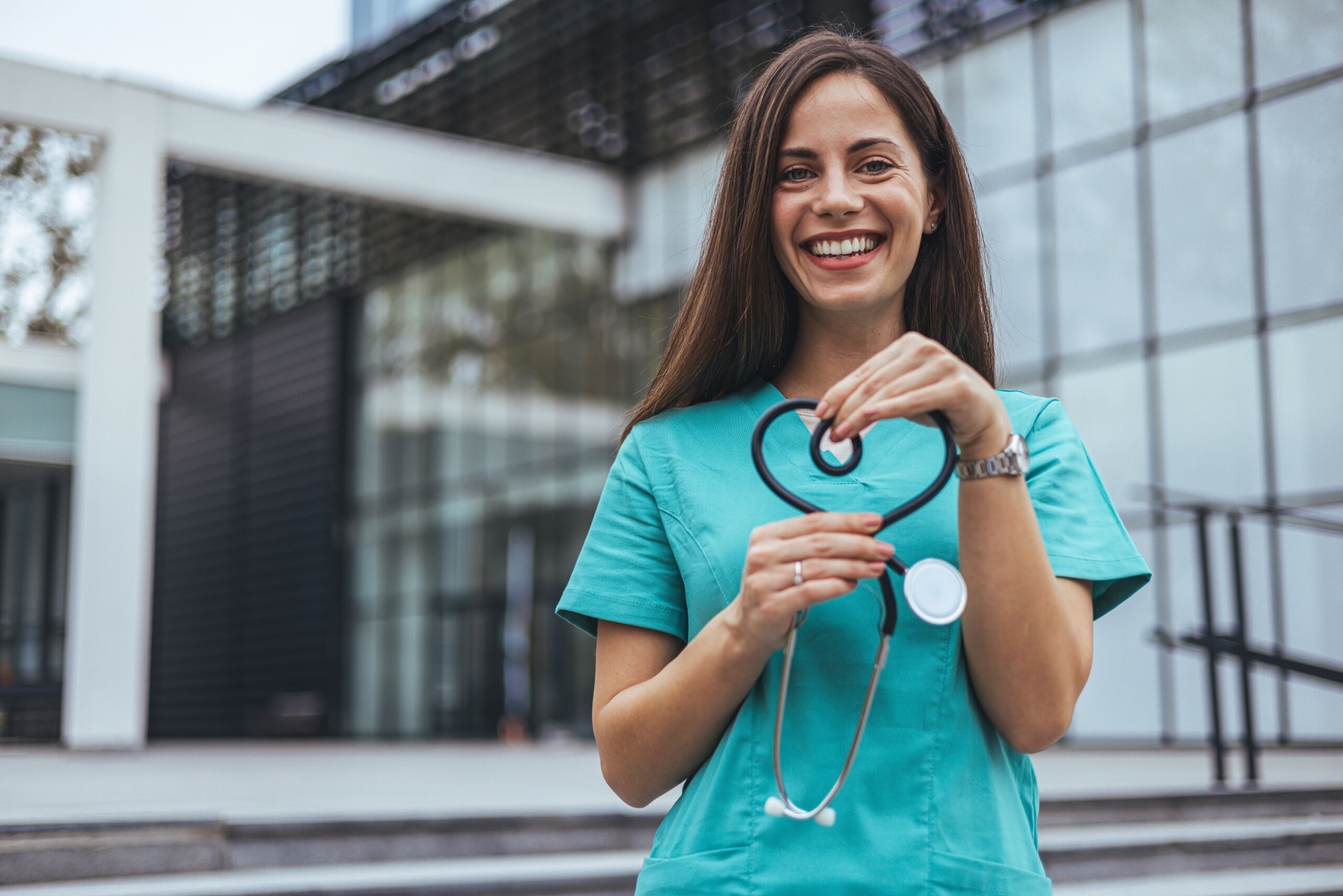 Joyful nurse forming a heart with her stethoscope