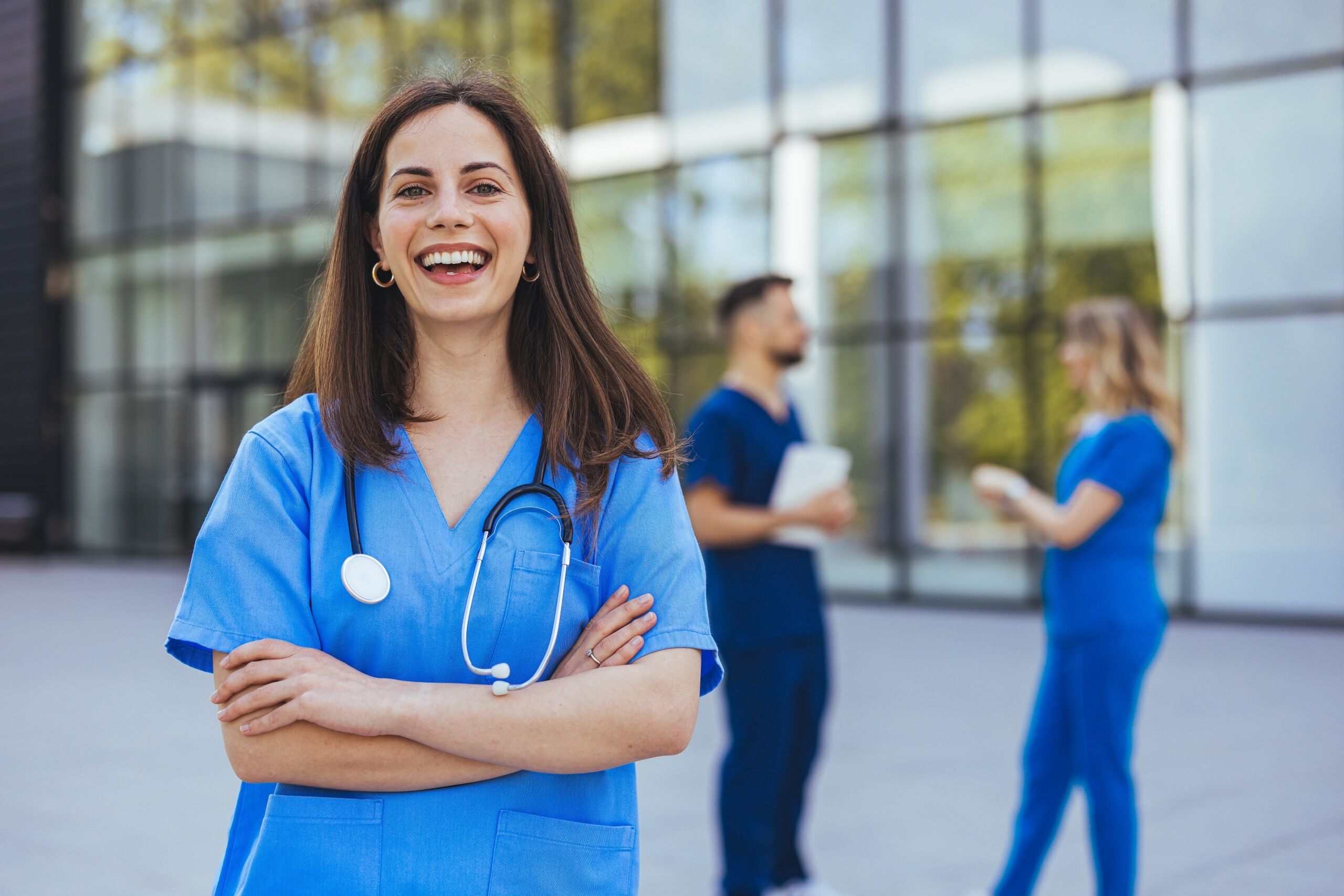 Cheerful medical professional standing in scrubs outside of a hospital