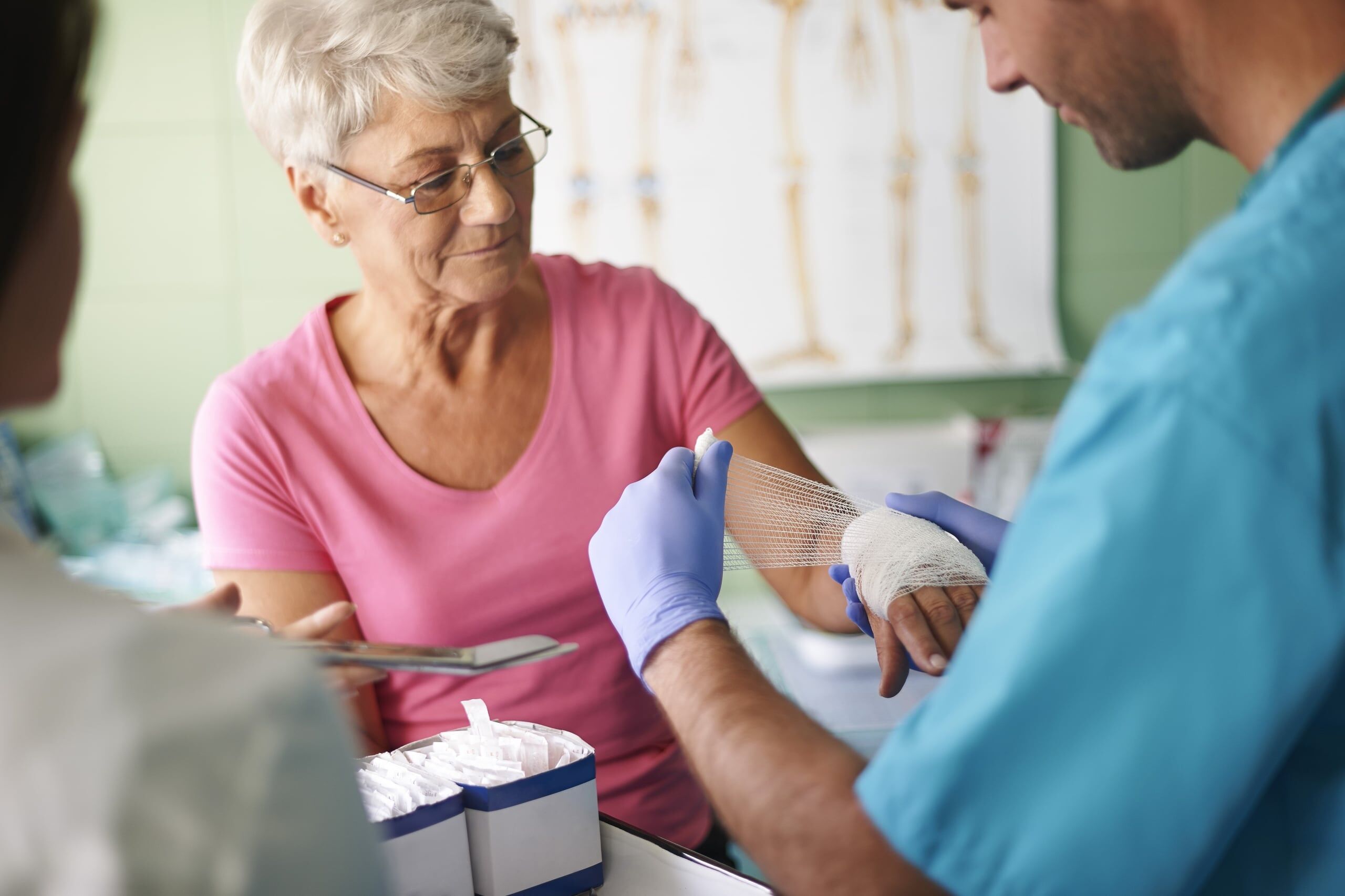 Nurse wrapping an elderly woman's hand in gauze