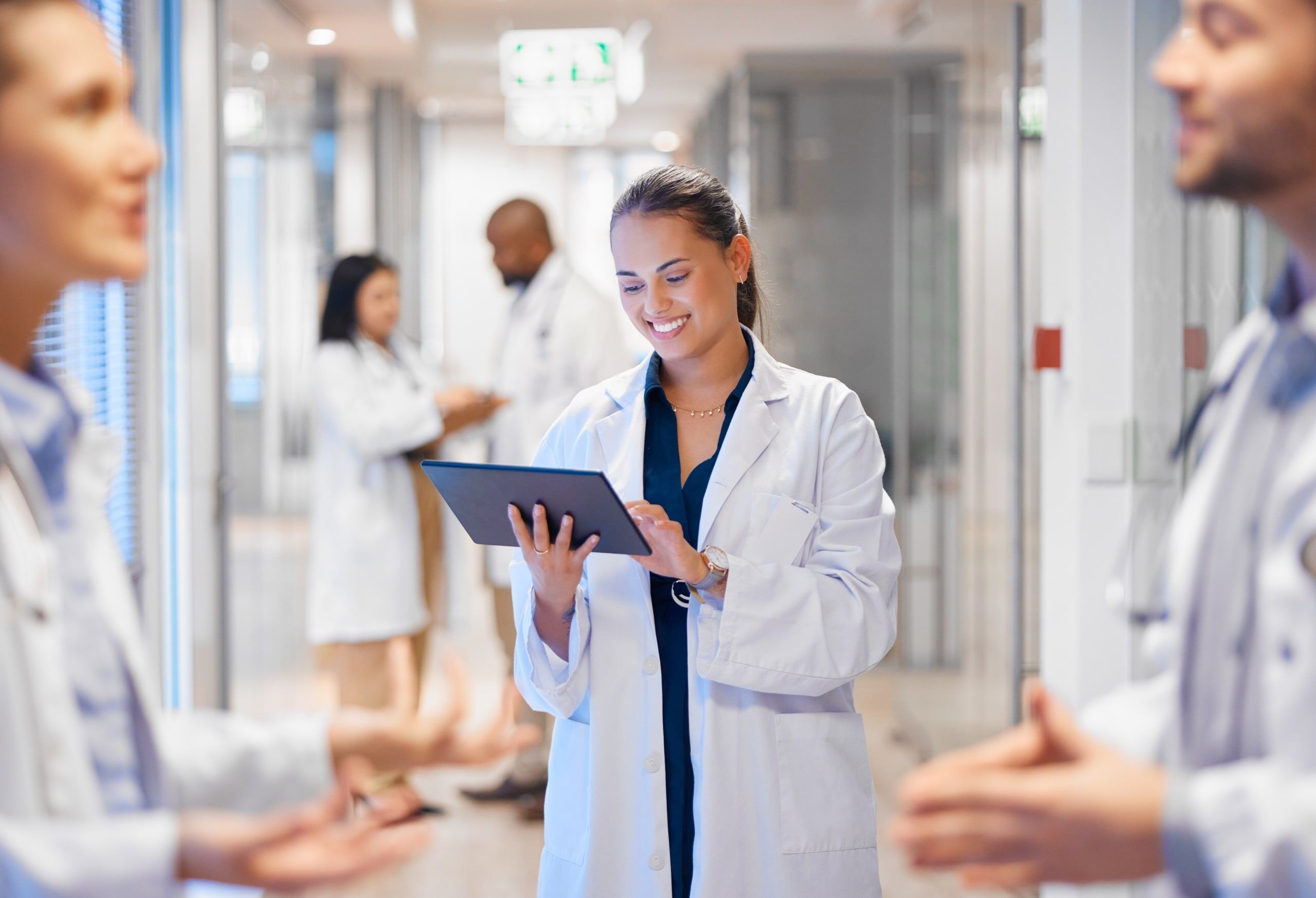 Nurse smiling at a tablet in a hospital hallway