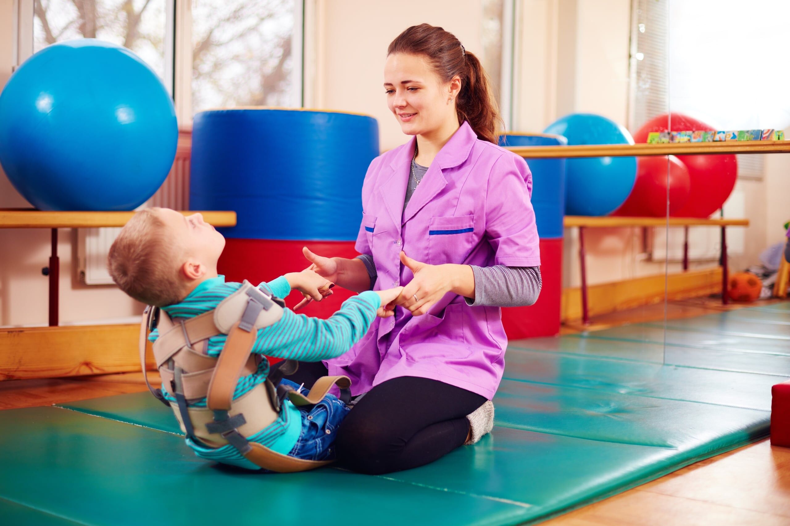 Physical therapy professional working with a child who has a disability