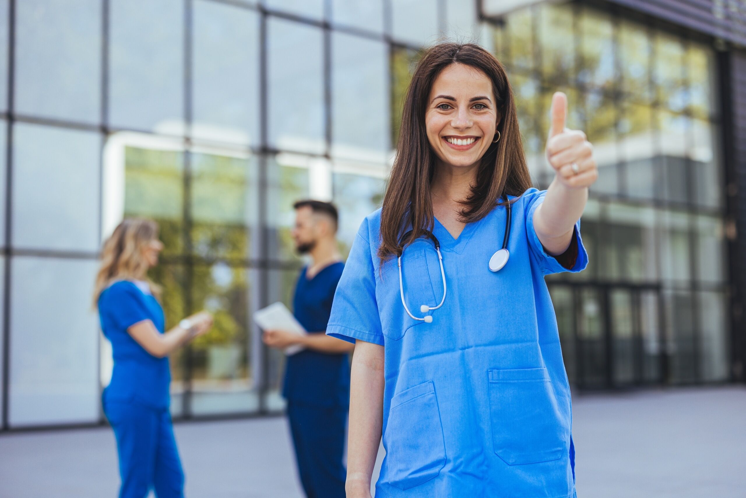 Nurse standing outside the hospital with a thumbs-up sign